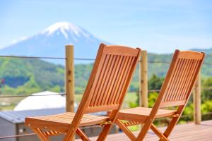 duas cadeiras de madeira sentadas num deque com uma montanha coberta de neve em グランファーム富士河口湖 em Fujikawaguchiko