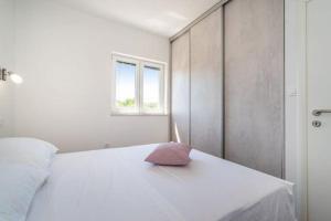- une chambre dotée d'un lit blanc avec un oreiller rose dans l'établissement Holiday House "Jere & Leon" - Villa With Sea View, à Ljubač