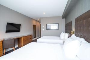 a hotel room with two beds and a tv at Sandman Hotel Hamilton in Hamilton