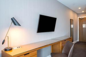a room with a desk with a television on a wall at Sandman Hotel Hamilton in Hamilton