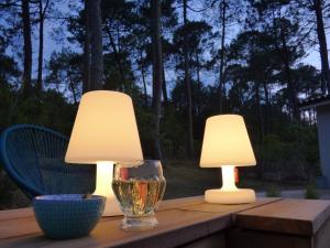 two lamps sitting on a table with a wine glass at Detached holiday home with private garden in Carcans