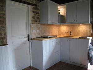 a kitchen with white cabinets and a sink at Cozy Holiday Home in Ceauc in Céaucé