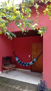 a hammock in front of a red building with a bench at Em Busca Hostel in Bonito