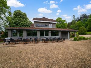 una casa con tavoli e sedie di fronte di Luxurious holiday home on the banks of the Ourthe a Barvaux-sur-Ourthe