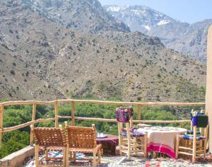 a table and chairs on a balcony with mountains at Toubkal Views in Imlil