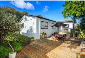 a house with a wooden deck with a table at Near motorway and supermarket in Auckland