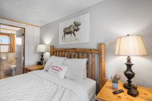 1 dormitorio con 1 cama y 1 mesa con lámpara en The Bucking Moose, en West Yellowstone