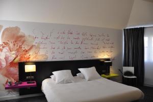 - une chambre avec un lit et un bureau sur le mur dans l'établissement Hôtel Les Astéries Lorient Ploemeur, à Ploemeur