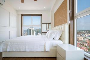 um quarto com uma cama branca e uma grande janela em Homestay Hạ Long 3 phòng ngủ view biển em Ha Long
