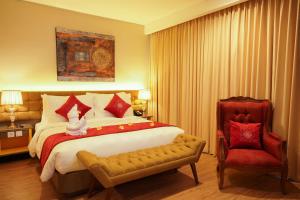 a bedroom with a large bed and a red chair at Ramada by Wyndham Yogyakarta in Yogyakarta