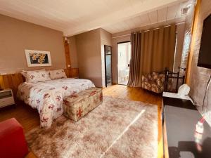 a large bedroom with a bed and a couch at Cantinho de Campos in Campos do Jordão
