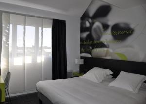 - une chambre avec un lit blanc et une grande fenêtre dans l'établissement Hôtel Les Astéries Lorient Ploemeur, à Ploemeur