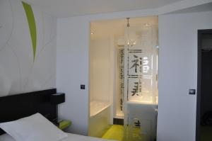 Cette chambre comprend un lit et une salle de bains pourvue d'une baignoire. dans l'établissement Hôtel Les Astéries Lorient Ploemeur, à Ploemeur