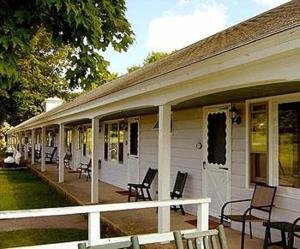 a porch of a white house with rocking chairs at West Road Motel in Bennington