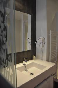 La salle de bains est pourvue d'un lavabo blanc et d'un miroir. dans l'établissement Hôtel Les Astéries Lorient Ploemeur, à Ploemeur