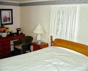a bedroom with a bed and a chair and a lamp at West Road Motel in Bennington +8 photos
