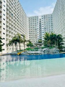 a large swimming pool with palm trees and buildings at 1 bedroom unit condo in Manila