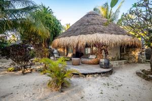 une petite cabane avec un toit de chaume sur la plage dans l'établissement Seed Resort, à Nembrala