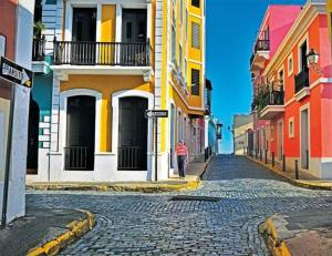 a man walking down a cobblestone street with colorful buildings at Domo Arigato 3 in San Juan