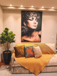 ein Sofa mit Kissen und ein Poster einer Frau in der Unterkunft Apto a 3 minutos da Rua Coberta de Gramado in Gramado