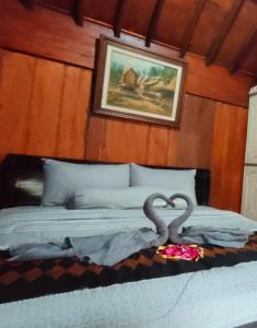 Una cama con dos cisnes haciendo un corazón en ella en Bujak Permai Villa Matahari Lombok NTB en Praya
