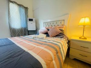 ein Schlafzimmer mit einem Bett mit einer Lampe und einer Kommode in der Unterkunft Tavalero Rooms in Santo Domingo