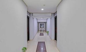 um corredor num edifício com paredes e colunas brancas em OYO Flagship Red Stay Near V3S Mall em Nova Deli
