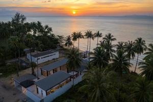 苏梅岛Villa Hanna Luxury Beachfront Koh Samui的日落时分海滩上度假村的空中景致