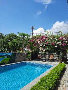 a swimming pool with pink flowers on a fence at Tam Coc Viet Ha Homestay in Ninh Binh
