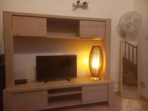 - une télévision à écran plat sur un centre de divertissement en bois avec une lampe dans l'établissement La Perle du Sable Blanc, à Saint-Gilles les Bains