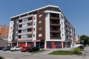 een appartementencomplex met auto's geparkeerd op een parkeerplaats bij Apartman Tija 3 in Subotica