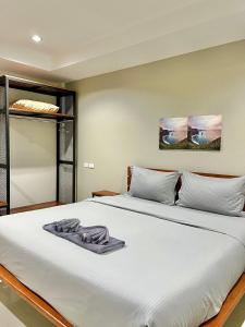 a bedroom with a large bed with white sheets at The Gun Hotel 8 in Surin