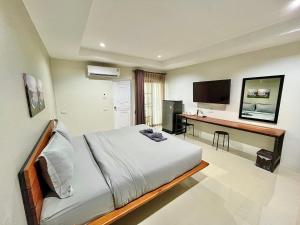 Dormitorio con cama, escritorio y TV en The Gun Hotel 8, en Surin