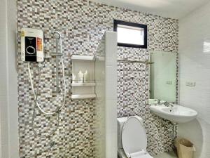 a bathroom with a shower and a toilet and a sink at The Gun Hotel Premium in Surin
