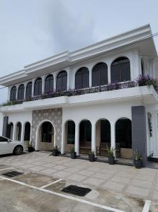a white building with a balcony with purple flowers at HOTEL SHAFURA 3 in Cukai