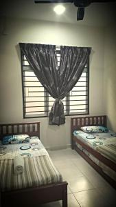 2 camas individuales en una habitación con ventana en Kirana Baiduri Homestay, en Nilai