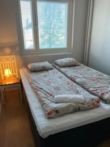 een slaapkamer met een bed met kussens en een raam bij Apartment Kustaa in Kokkola