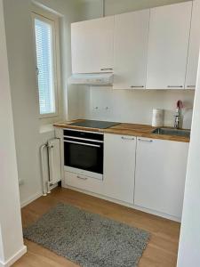 een keuken met witte kasten en een zwarte oven bij Apartment Kustaa in Kokkola