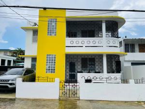 a yellow house with a car parked in front of it at Jireh 1 ¤ Near to Airport¤ in San Juan