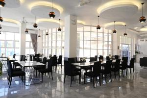 un comedor con mesas, sillas y ventanas en J&V Hotel and Resort en Apaleng