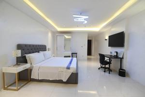 1 dormitorio con 1 cama, escritorio y TV en J&V Hotel and Resort, en Apaleng
