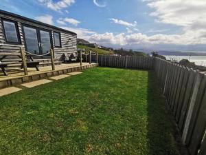 a backyard with a house and a fence at Allibella Shepherds Hut, Amazing Seaview, Private garden, Pet Friendly in Barmouth +14 photos