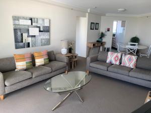 ein Wohnzimmer mit 2 Sofas und einem Glastisch in der Unterkunft Ocean Plaza Resort in Gold Coast