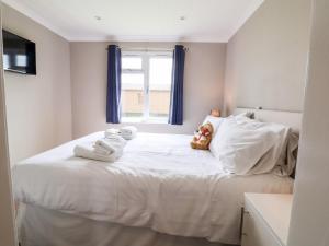 a white bed with towels and a teddy bear on it at Callow Lodge 15 in Hadnall