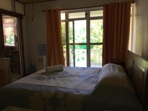 a bedroom with a bed in front of a window at Pension Te Aroha - Te Arii in Maatea