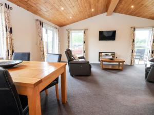 uma sala de estar com uma mesa de madeira e cadeiras em Callow Lodge 5 em Hadnall