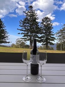 a bottle of wine and two wine glasses on a table at Three Pines House - Unique Tiny House with Views in Mount Tamborine
