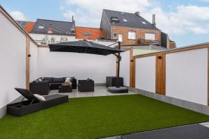 an outdoor patio with green grass and an umbrella at Beautiful modern holiday house with private garden in Bredene