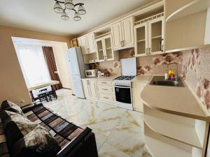 a kitchen with white cabinets and a sink and a couch at Sun Hall in Lviv