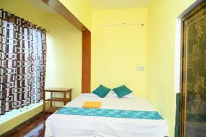 Un dormitorio con una cama con almohadas azules y una ventana en OYO Hotel River, en Bhilai